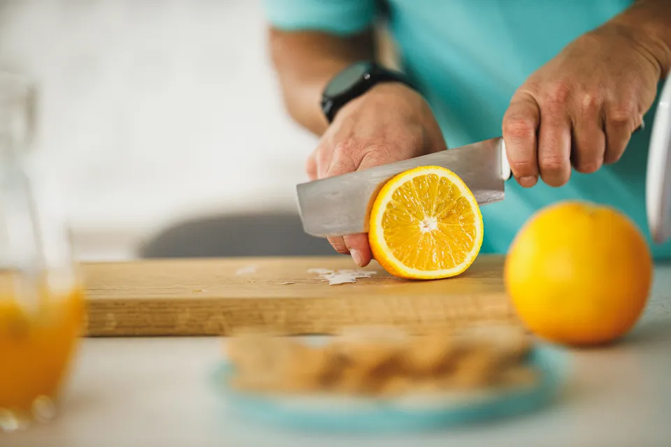 Person slicing an orange on a cutting board