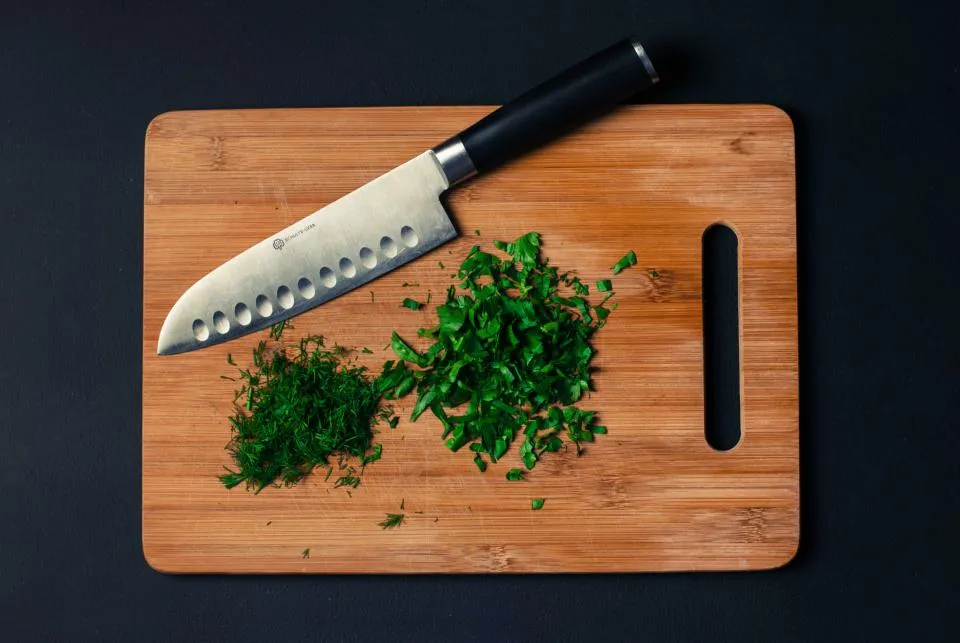 Chef's knife and chopped herbs on a cutting board